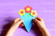 Small child made paper flowers crafts for mother's day or birthday. Child holds and shows a paper bouquet. Easy, quick and beautiful gift for mommy