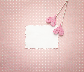 Blank paper card with decorative hearts on a pink polka dots background.