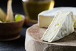 Closeup of soft cheese brie sliced on wooden cut with honey and pear on dark rustic background