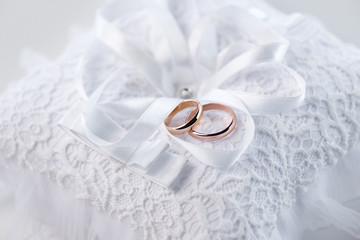 Close-up view of golden wedding rings on decorative white lace pillow