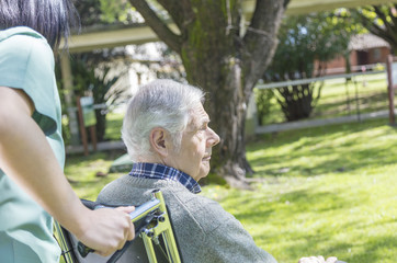 Poster - Elderly male patient on wheelchair helped by nurse