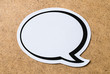 Large blank speech bubble on a light brown wooden cork board background. Chat bubble cut from paper and cardboard. Message, chat and communication concept with a lot of free empty copy space for text.