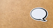 Wooden cork board background texture with a blank speech bubble in the right side. Chat bubble cut from paper and cardboard. Banner style communication, chat and social media concept with copy space.
