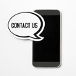 Contact us text in a speech bubble with a smartphone. Speech balloon cut from cardboard. Information button, icon or banner for website, social media or brochure with a white paper background.