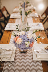 Wall Mural - The wooden festive table is decorated with compositions of flowers, candles and served with cutlery, glasses and plates