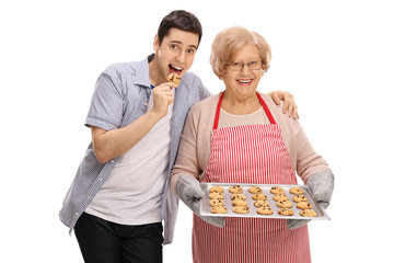 Sticker - Young man tasting freshly baked cookie by his grandmother