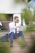 © nikodash - Handsome young businessman working on laptop sitting on the stairs outdoor