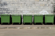 Green Garbage Containers Standing In A Row In The Backyard Of An Industrial Building.