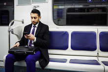 Portrait Of Middle-Eastern Businessman Commuting To Work In Subway Train, Using Smartphone To Listen To Music