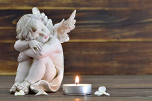 Angel And Burning Candle On Wooden Background