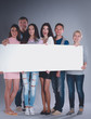© shefkate - Happy young group of people standing together and holding a blank