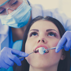 Wall Mural - Woman dentist working at her patients teeth