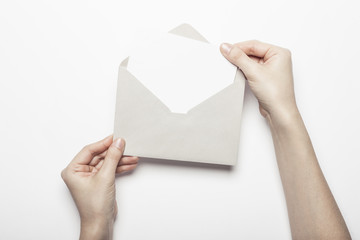 woman hand hold a envelope with post card on the white table.