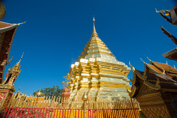 Gold pagoda and gold buddha statue with blue sky at Wat Phra That Doi Suthep, Chiang Mai, Thailand.