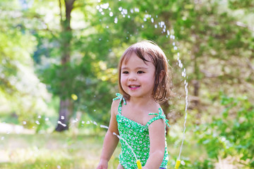 Wall Mural - Happy toddler girl playing with sprinkler