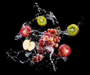 Set of fresh fruits in water splash over black background