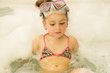 © Fotos 593 - little beautiful girl playing with water and foam in bath using a swimsuit and beautiful dive sunglasses