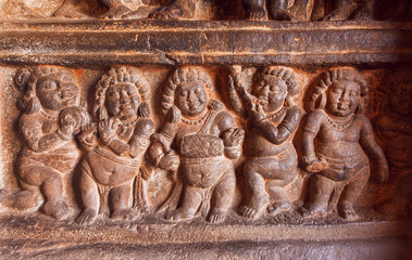 Canvas Print - Example of Indian art carvings with singing and dancing party of ancient people on wall of 6th century temples in Badami, India