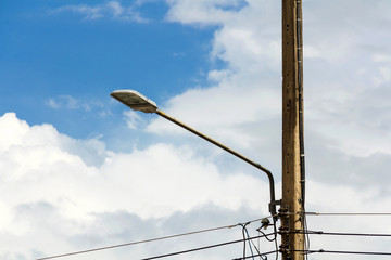 Electric light and power poles with wires in an electric blue sky on background