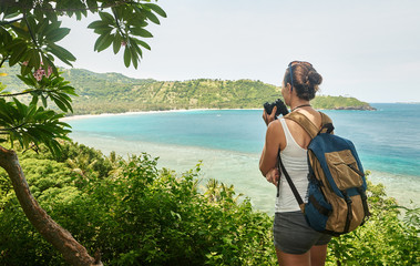 Wall Mural - Traveller with backpacker holds binoculars in hands enjoying view beatiful coast