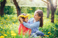 Beautiful Blue-eyed Girl Wears A Wreath Of Dandelions To Her Sister On The Head