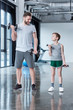 © LIGHTFIELD STUDIOS - Boy training with dumbbells together with coach at fitness center