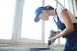 © pressmaster - Side view portrait of young woman working with power drill, installing PVC windows