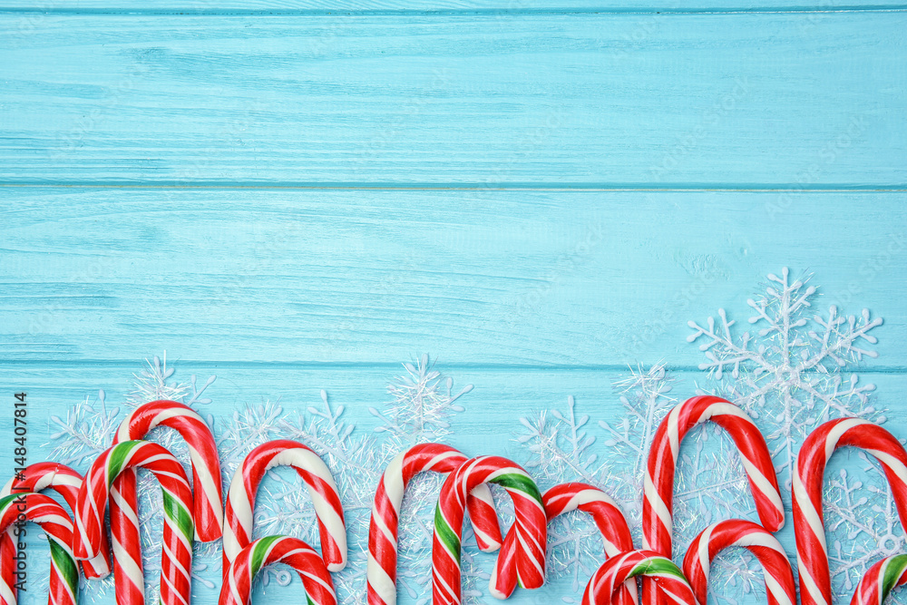 Christmas candy canes and decor on color wooden background