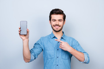 Sticker - Portrait of happy young man pointing with his finger on the screen of his smartphone on light blue background