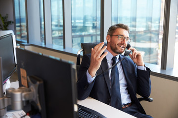 businessman making phone call sitting at desk in office