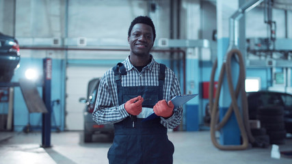 Smiling African mechanic writing out a job sheet for repairs to a vehicle with the attractive woman owner of the car alongside explaining the problems