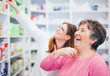 © Karanov images - Pharmacist and senior costumer looking and searching for a medication on pharmacy shelf laughing