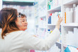 © Karanov images - Pharmacist discusses medication assortment with senior customer beside pharmacy shelf