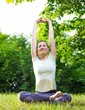 © disq - Active Young woman  training yoga outdoors. Woman doing exercise in summer nature foliage background.