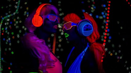 Poster - two female gogo ravers in fluorescent costume dancing in disco setting