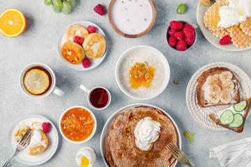 Morning atmosphere. Healthy breakfast with porridge, oatmeal, pancakes, lots of berries and snacks on blue rustic background.