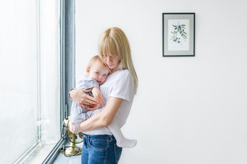 A baby daughter in the hand of his mother at the window