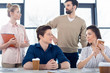 © LIGHTFIELD STUDIOS - group of young business people looking at each other at workplace in small business office