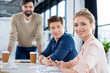 © LIGHTFIELD STUDIOS - smiling businesswoman sitting at table with colleagues on business meeting