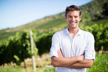 Portrait of smiling man with arms crossed standing at vineyard