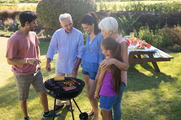 Family talking while preparing barbecue in the park