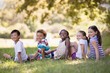 © WavebreakMediaMicro - Smiling friends sitting on grass at campsite