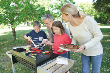 Family preparing grilled meet on barbecue