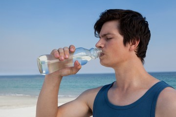 Poster - Man drinking water from bottle at beach