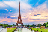Fototapeta Boho - Eiffel tower, view from Trocadero park over fountain. People making their evening promenade around fountain. Eiffel tower is famous symbol of Paris city and France. Sunset scenery, epic dramatic sky.