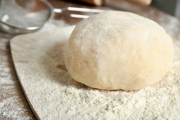 Canvas Print - Board with raw dough on kitchen table, closeup