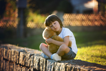 Canvas Print - Sweet boy, playing with teddy bear on a small rural path on sunset