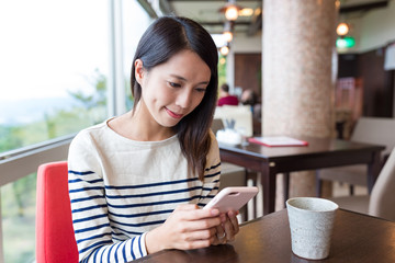 Wall Mural - Woman sending sms on cellphone in cafe