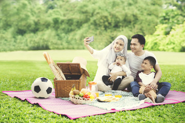 Wall Mural - Muslim family with smartphone in the park