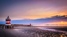 Beautiful Sunrise At The Seaside In Italy, At Lignano Sabbiadoro, With Pier And Lighthouse In The Foreground.